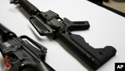 FILE - In this Jan. 11, 2018, photo, a semi-automatic rifle at right that has been fitted with a so-called bump stock device to make it fire faster, sits on a table at the Washington State Patrol crime laboratory in Seattle.