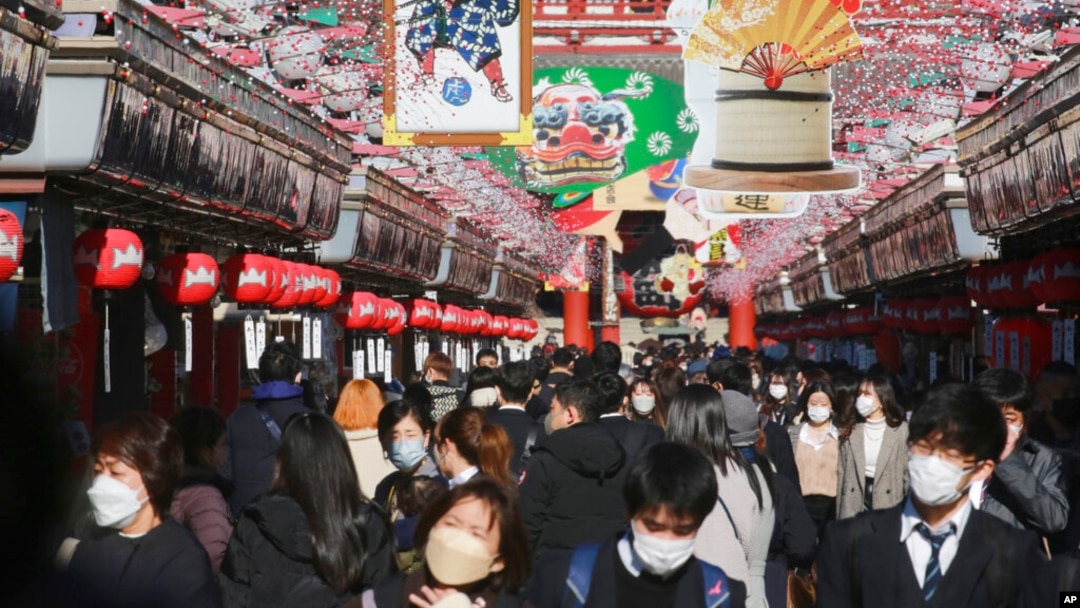 People wearing face masks to protect against the spread of the coronavirus walk under decorations for new year through the alley leading to Asakusa Sensoji Buddhist temple in Tokyo, Dec. 21, 2021. 