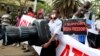 A Kenyan journalist carries a giant plastic replica of a camera as he participates in a protest along the streets of the capital Nairobi, Dec. 3, 2013. 
