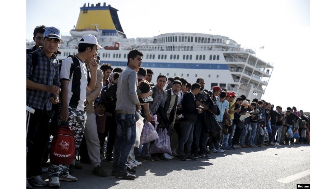 FILE - Refugees and migrants line up to board buses at the Greek port of Piraeus, near Athens, Oct. 15, 2015.