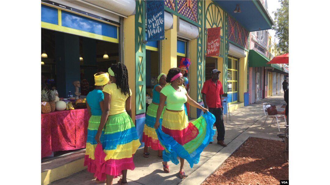 Creole dancers buy a fruit drink from a vendor at the Caribbean Marketplace in Little Haiti, Miami, Florida. (Photo: S. Lemaire / VOA)
