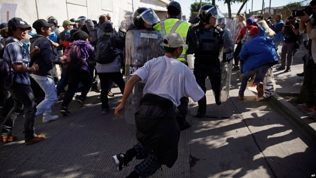 Migrants break past a line of police as they run toward the Chaparral border crossing in Tijuana, Mexico, Nov. 25, 2018, near the San Ysidro entry point into the U.S.