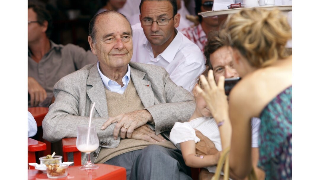 FILE - France's former President Jacques Chirac poses as a womans takes a picture of him sitting at a table outside the famous Le Senequier cafe in the French Riviera searesort of Saint-Tropez, Aug. 14, 2011.
