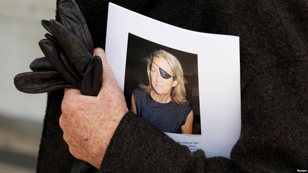 FILE - A man holds a sign honoring Sunday Times journalist Marie Colvin after a memorial service, outside St. Martin in the Field in London, May 16, 2012. 