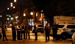 FILE - Police officers investigate at the scene of a shooting outside a funeral home in Chicago, July 21, 2020.