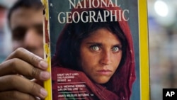 Pakistan's Inam Khan, owner of a book shop shows a copy of a magazine with the photograph of Afghan refugee woman Sharbat Gula, from his rare collection in Islamabad, Pakistan, Oct. 26, 2016. 