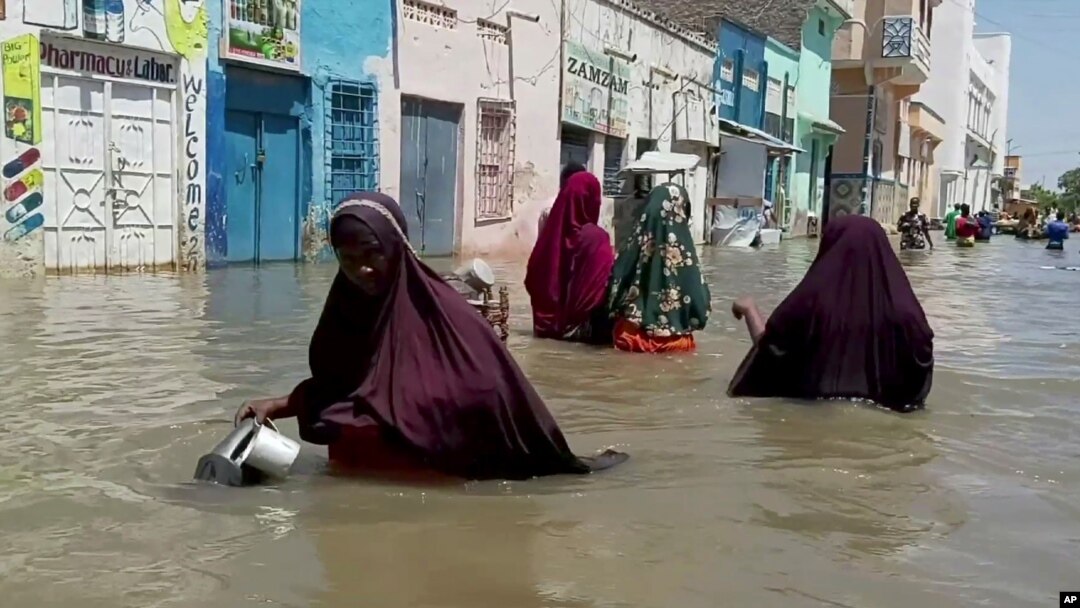 FILE - People wade through a flooded street in Beledweyne, central Somalia, in this image made from video, May 17, 2020. 
