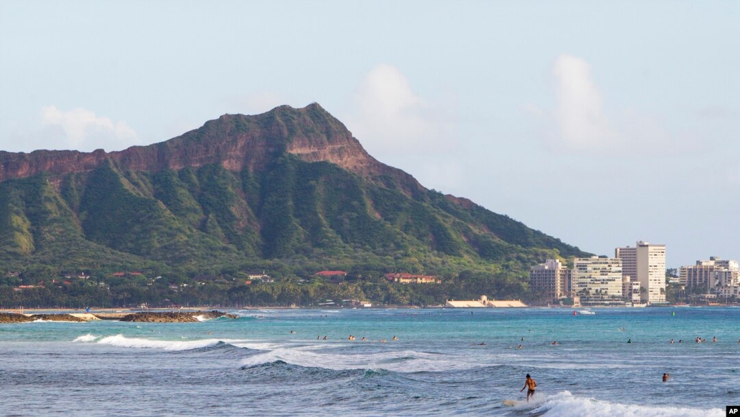 FILE - Surfers ride waves off Ala Moana Beach Park in Honolulu, with Diamond Head mountain in the background. Out of sight of tourists are disused military tunnels beneath the crater.