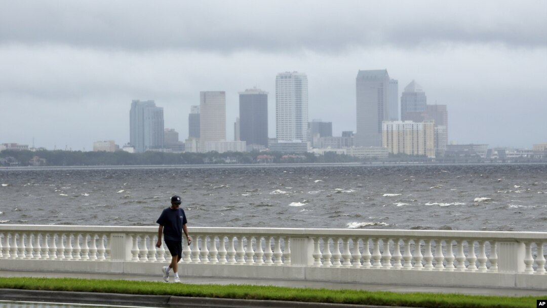 A resident walks along Bayshore Boulevard in between squalls blowing across the bay in Tampa, Florida, Monday, Aug. 27, 2012.