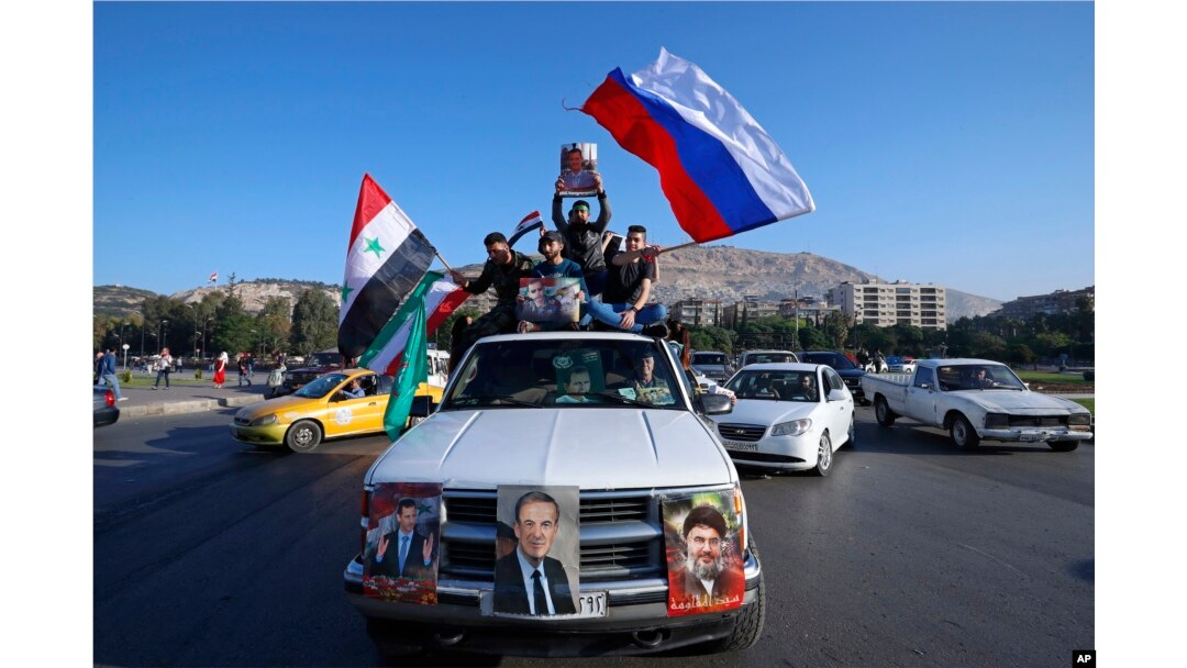 Syrian government supporters wave Syrian, Iranian and Russian flags as they chant slogans against U.S. President Trump during demonstrations following a wave of U.S., British and French military strikes.