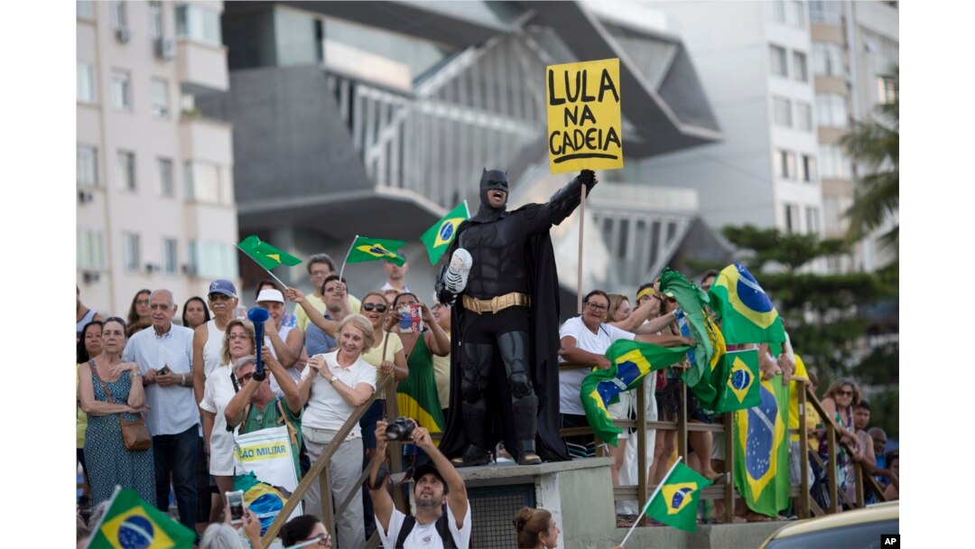 A demonstrator dressed as Batman holds a sign that reads in Portuguese "Lula in Prison" during a protest against former President Luiz Inacio Lula da Silva on Copacabana beach, in Rio de Janeiro, Brazil, Jan. 23, 2018.