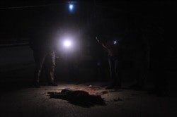 FILE - Somali security officers look at the body of a suspected al-Shabab fighter in Mogadishu, Somalia, Nov. 5, 2016. The U.S. military says 18 al-Shabab members were killed in an airstrike in southern Somalia.