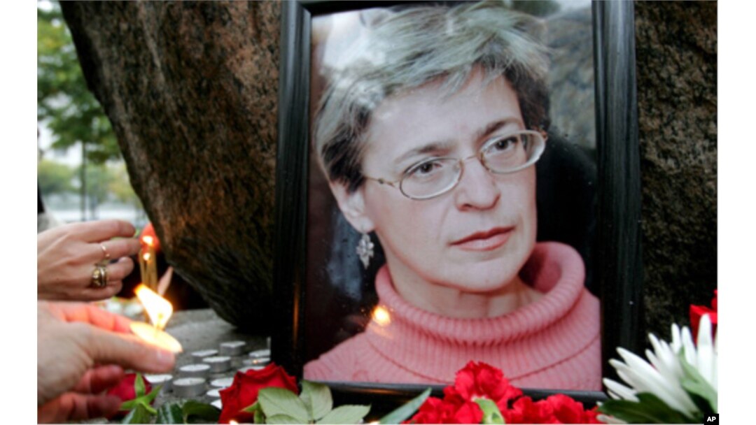 FILE - People light candles next to a portrait of Russian journalist Anna Politkovskaya during a rally in St. Petersburg in 2006.