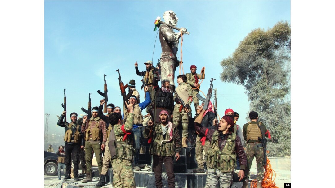 Turkey-backed Free Syrian Army soldiers celebrate around a statue of Kawa, a mythology figure in Kurdish culture as they prepare to destroy it in city center of Afrin, northwestern Syria, March 18, 2018.