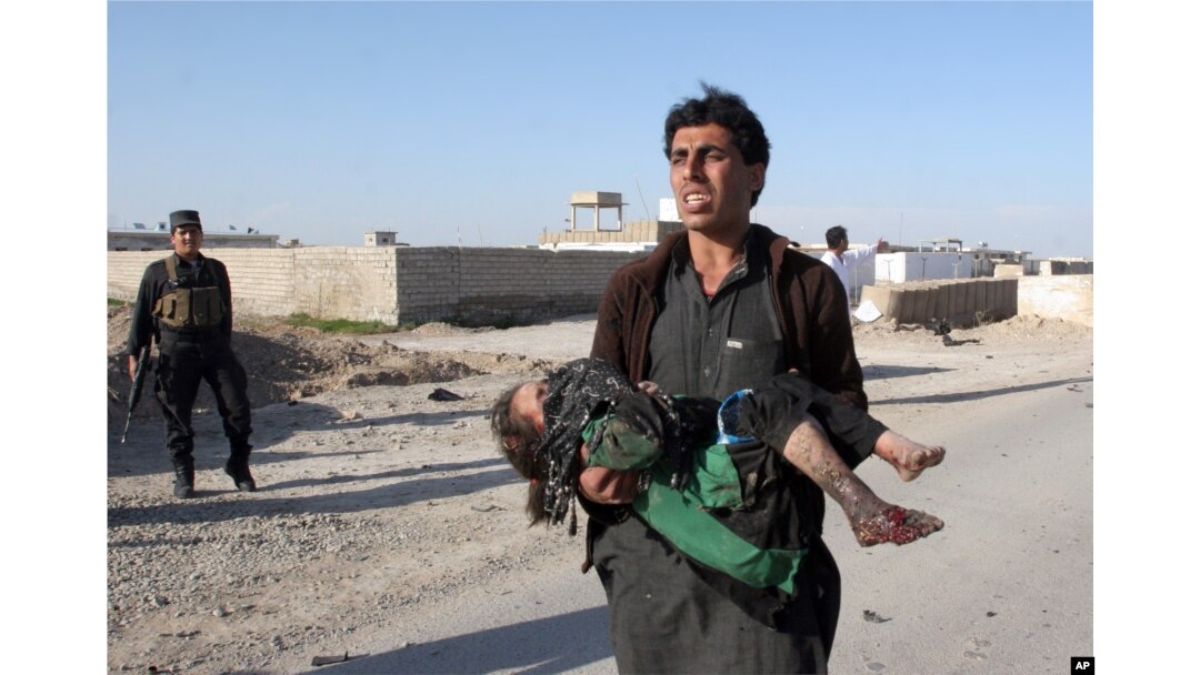 FILE - An Afghan man carries a wounded girl at the side of a suicide attack that killed civilians and a policeman in Lashkar Gah, the capital of Helmand province, south of Kabul, Afghanistan, March 16, 2015.