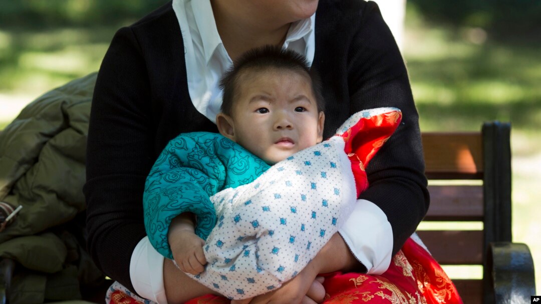 A child is wrapped up against the cold at a park in Beijing, China, Oct. 30, 2015. Shares of companies making diapers, baby strollers and infant formula got a boost Friday from China's decision to scrap its one-child policy.