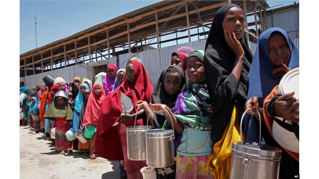 FILE - In this photo taken Feb. 25, 2017, displaced Somali girls who fled the drought in southern Somalia stand in a queue to receive food handouts at a feeding center in a camp in Mogadishu, Somalia.