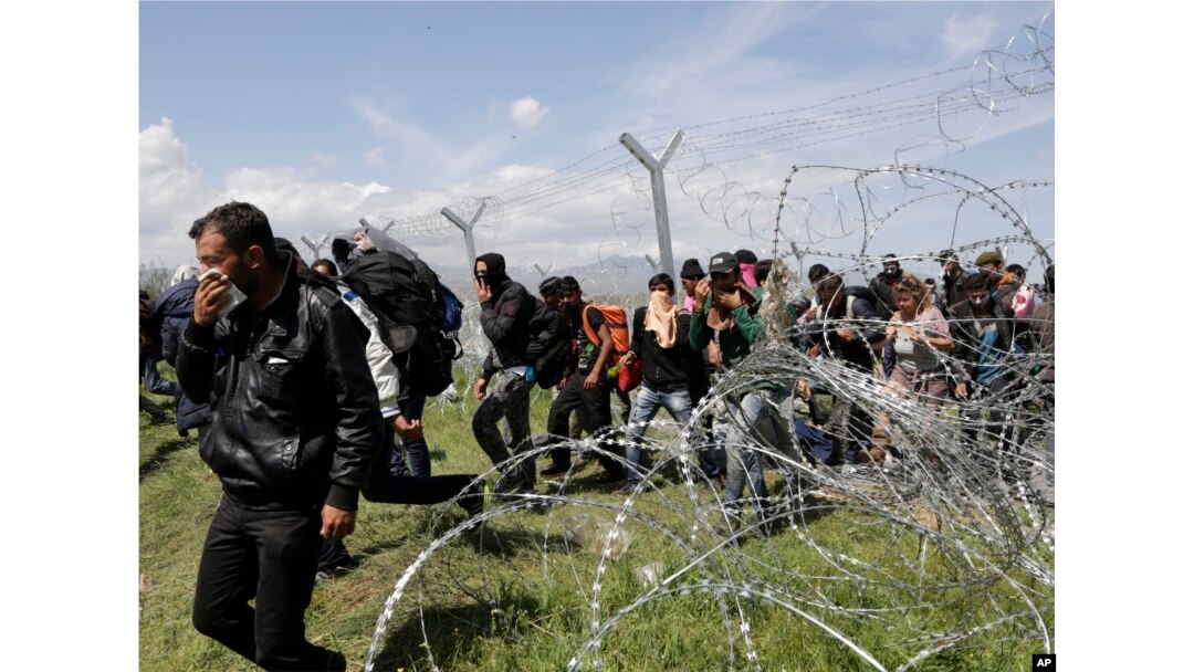 Migransts exit through a broken fence after a protest at the northern Greek border point of Idomeni, Greece, April 10, 2016.