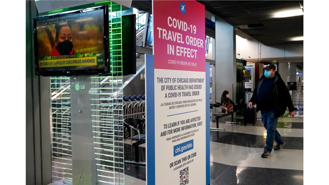 A traveler walks through Terminal 3 as a COVID-19 travel order sign is displayed at O'Hare International Airport in Chicago, Sunday, Nov. 29, 2020. Friday's total of new cases is the next-to-lowest daily number in the past 12 days, but Illinois…