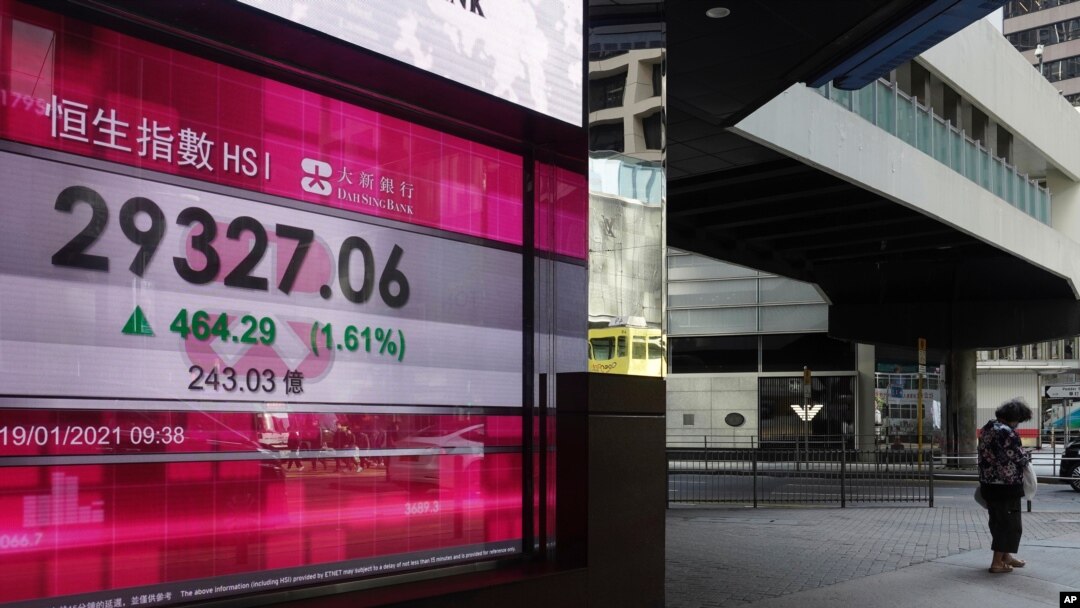 A woman walks past a bank's electronic board showing the Hong Kong share index at Hong Kong Stock Exchange in Hong Kong, Jan. 19, 2021.