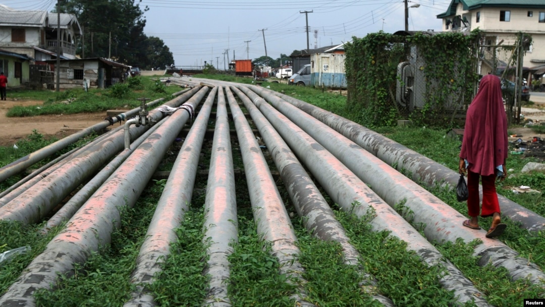 FILE - A girl walks on a gas pipeline running through Okrika community near Nigeria's oil hub city of Port Harcourt.