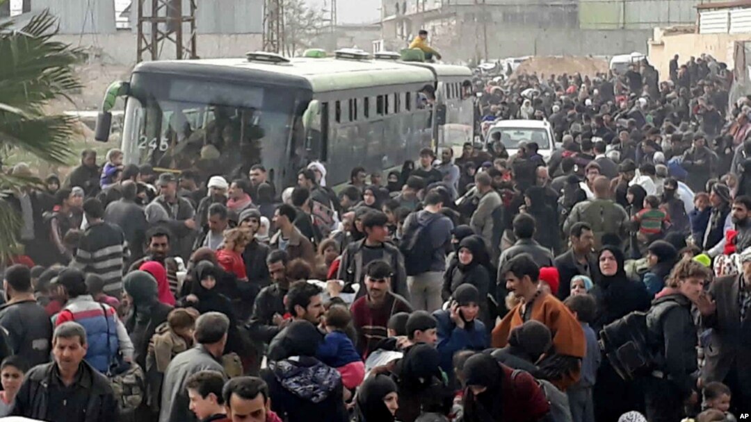 This photo released by the Syrian official news agency SANA, shows Syrian civilians with their belongings, fleeing from fighting between the Syrian government forces and rebels, in eastern Ghouta, a suburb of Damascus, Syria, March. 15, 2018. 
