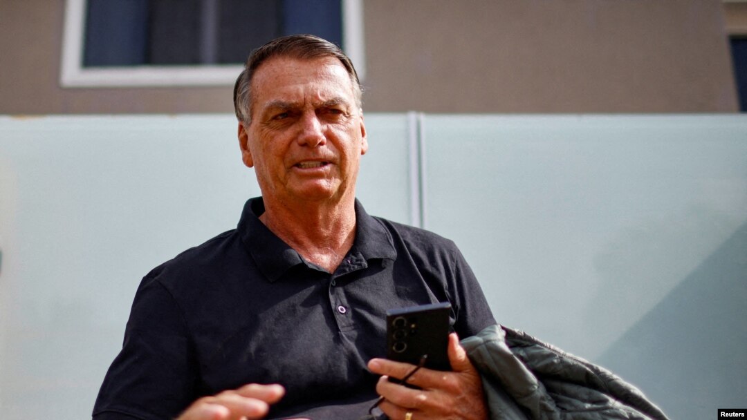 FILE - Former Brazilian President Jair Bolsonaro stands in front of his house before testifying to the federal police in Brasilia, Feb. 22, 2024. Judicial papers released March 15 say Bolsonaro presented military leaders with a plan to reverse the 2022 election if he lost. 