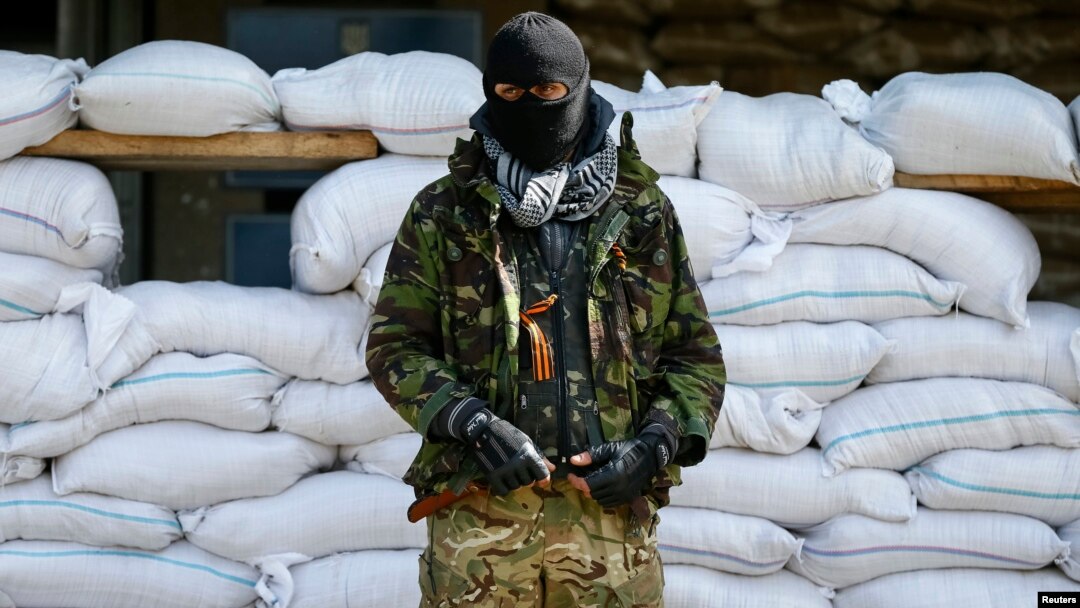 An armed man, who is wearing black and orange ribbons of St. George - a symbol widely associated with pro-Russian protests in Ukraine, stands guard in front of barricades outside the mayor's office in Slovyansk April 18, 2014. 
