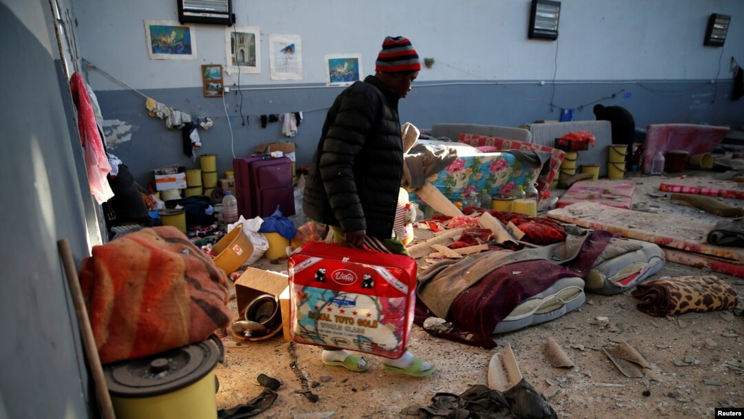 FILE - A migrant carries his belongings at a detention center for mainly African migrants, that was hit by an airstrike in the Tajoura suburb of Tripoli, Libya, July 3, 2019.