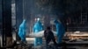 Health workers in personal protective equipment carry the body of a COVID-19 victim for cremation in New Delhi, India, Nov. 19, 2020.