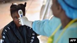 This file photo taken on Aug. 16, 2014 shows a girl suspected of being infected with the Ebola virus having her temperature checked. Four people have been confirmed to have Ebola in Guinea a MSF official said on Feb. 15, 2021.
