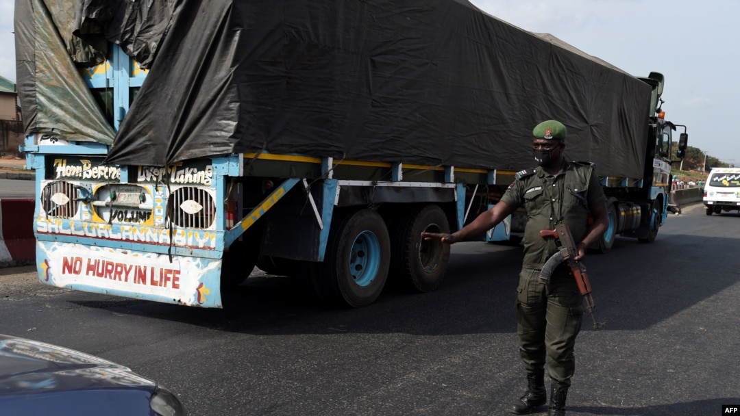 A police officer, wearing a face mask customised for the anti-robbery Rapid Respond Squad (RRS) as preventive measure against the COVID-19 coronavirus, flags down a car at a check point in Lagos, on April 20, 2020. 
