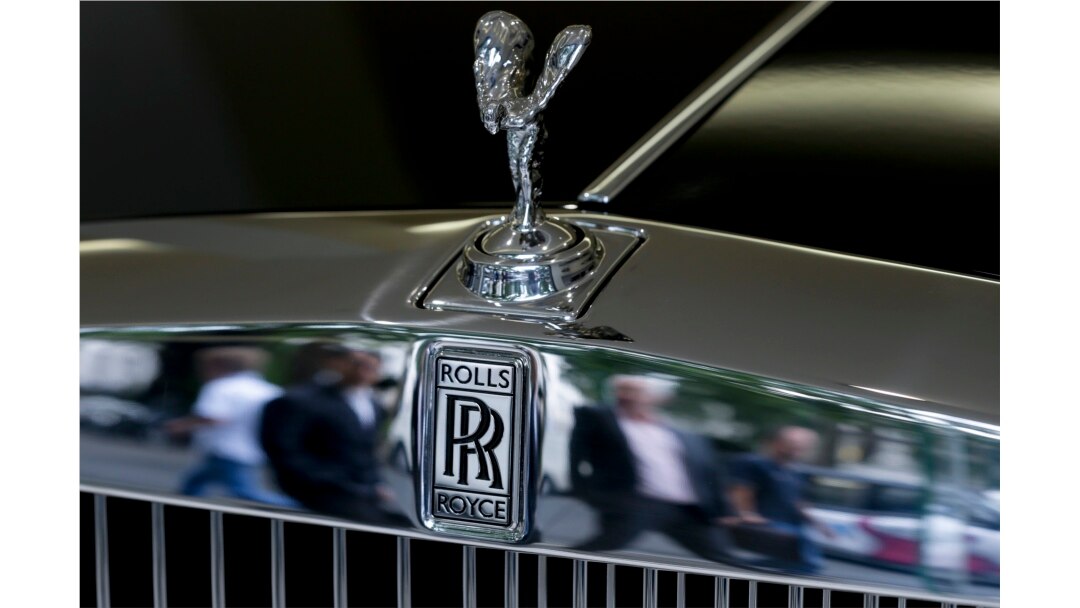 FILE - Pedestrians are reflected in the front of a Rolls-Royce in a London showroom, July 8, 2014. A reality TV personality in Georgia is accused of using a $2 million small-business loan to buy a Rolls-Royce.