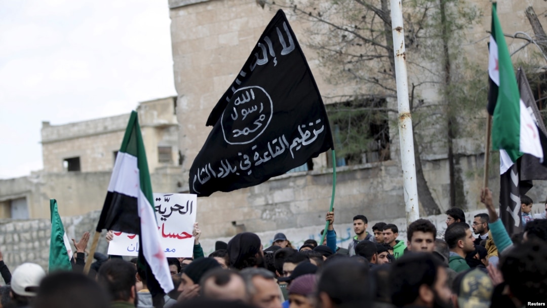 FILE - Protesters carry Al-Qaida flags during an anti-government demonstration after Friday prayers in the town of Marat Numan in Idlib province, Syria, on March 11, 2016.
