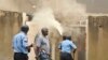 Policeman armed with pistol and tear gas patrols while firemen extinguish fire set by rioting youth at Salvation Army Church, Mombasa, Kenya, Oct. 4, 2013.