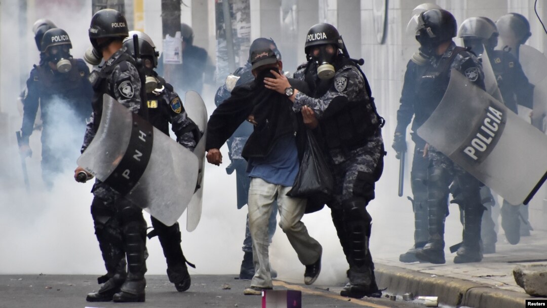 Police help a pedestrian overcome by tear gas as supporters of Salvador Nasralla, presidential candidate for the Opposition Alliance Against the Dictatorship, clash with police during a protest caused by the delayed presidential vote count, Dec. 1, 2017.