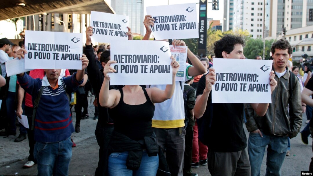 Residents hold up signs that read, "Metro workers: The people support you," outside Ana Rosa subway station during the fifth day of metro worker's strike in Sao Paulo, Brazil, June 9, 2014.