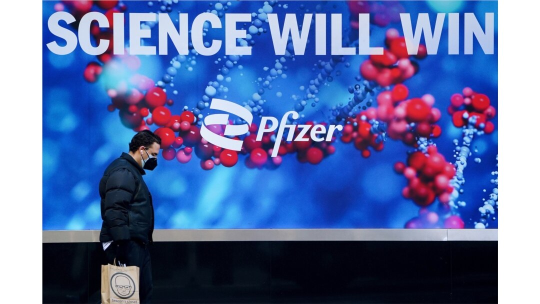 FILE - A person walks past the Pfizer building in Manhattan, New York City, March 2, 2021.