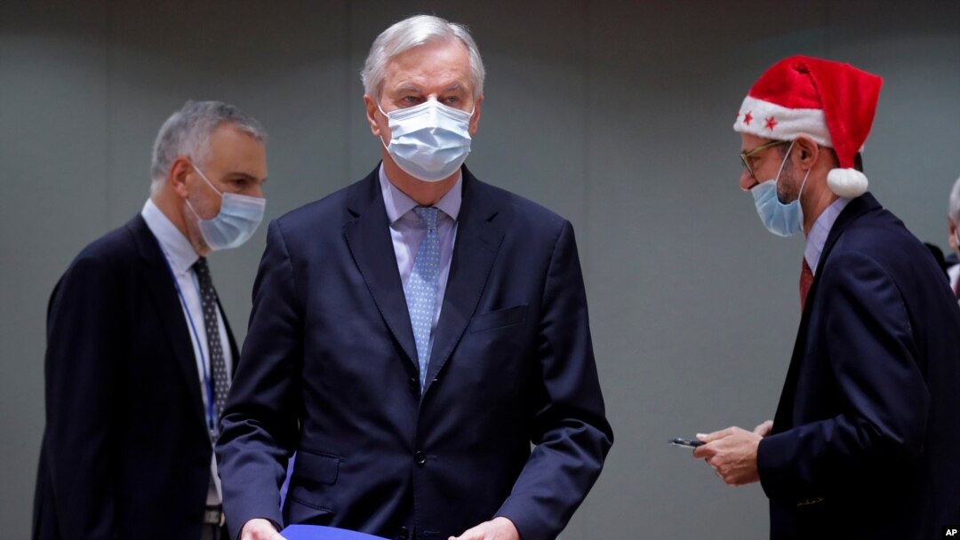 European Union chief negotiator Michel Barnier, center, carries a binder of the Brexit trade deal during a special meeting of Coreper, at the European Council building in Brussels, Dec. 25, 2020.