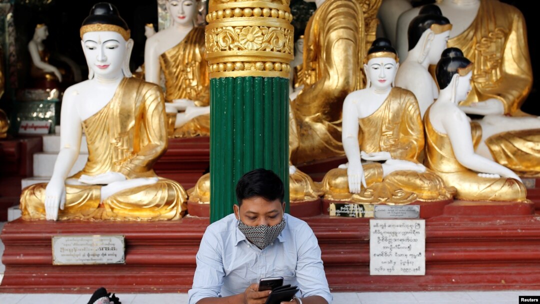 A man wears a face mask as he uses his phone at Shwedagon Pagoda in Yangon, Myanmar January 31, 2020. REUTERS/Ann Wang