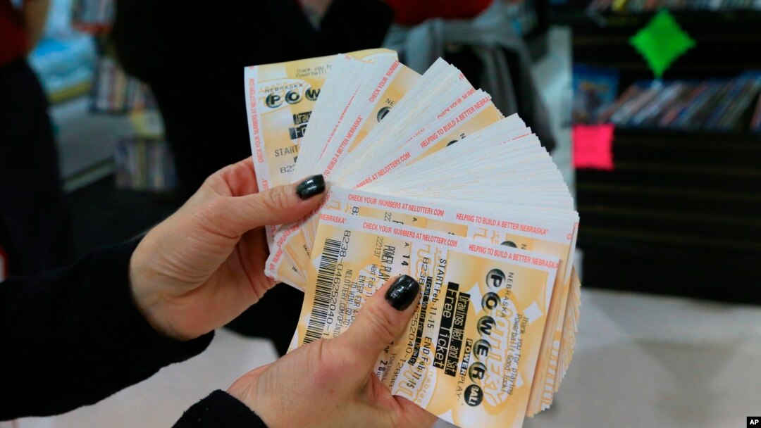 A lottery representative hands out free Powerball tickets at Russ's Market in Lincoln, Neb., as part of a promotion, Wednesday, Feb. 11, 2015.