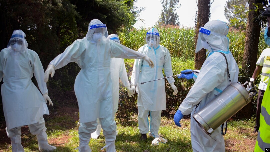 FILE - Health workers wearing protective suits prepare to bury coronavirus victim Dr. Doreen Adisa Lugaliki, at her funeral in Ndalu, Bungoma county, Kenya, July 13, 2020.