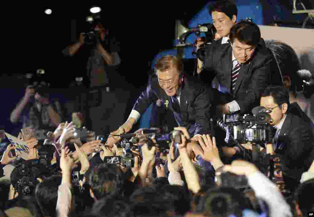 South Korea's presidential candidate Moon Jae-in of the Democratic Party is greeted by supporters as he arrives to give a speech on a stage in Seoul. Moon declared victory in the country's presidential election, setting up its first liberal rule in a decade.