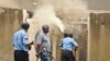 An armed policeman carrying a pistol and tear gas patrols while firemen attempt to put out a fire in the Salvation Army Church after it was set on fire by rioting youths, following Friday Muslim prayers in Mombasa, Kenya, Oct. 4, 2013.