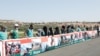 Healthcare workers hold signs near Bab al-Hawa crossing during a sit-in against its closure, at the Syrian-Turkish border, in Idlib governorate, Syria, July 2, 2021.