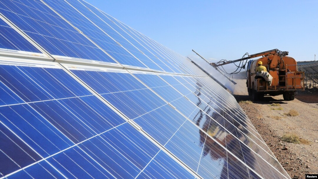 FILE - A worker operates machinery to clean solar panels at a photovoltaic industrial park in Hami, Xinjiang Uyghur Autonomous Region, China, Oct. 22, 2018.