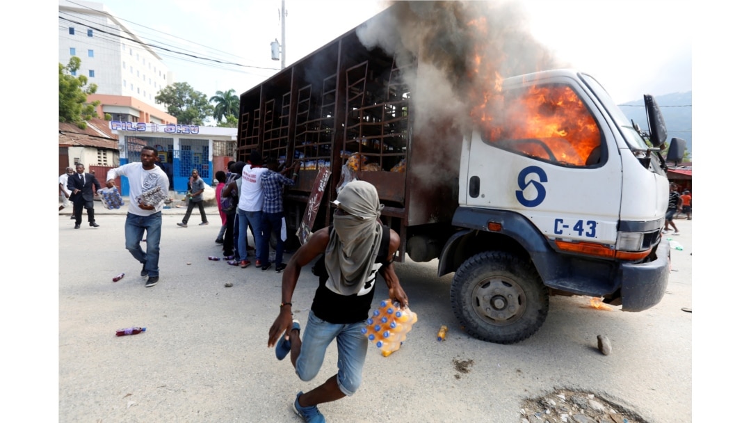 Demonstrators loot a burning truck after the wake of demonstrators killed during the protests to demand the resignation of Haitian president Jovenel Moise in Port-Au-Prince, Haiti, Nov. 19, 2019.