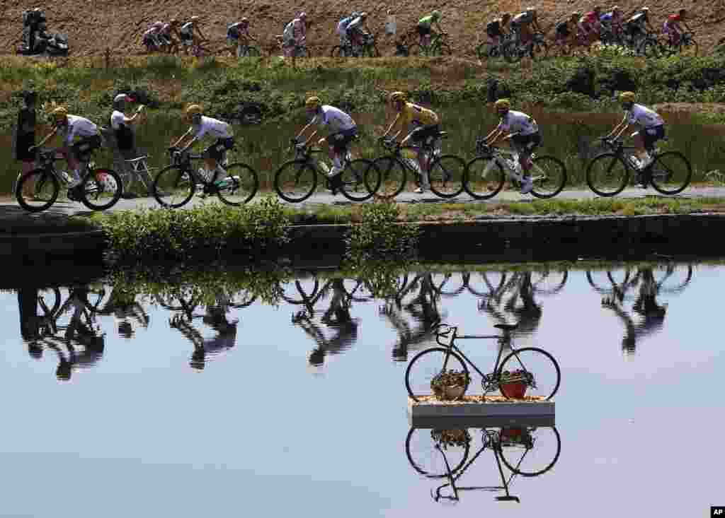 Britain&#39;s Geraint Thomas, wearing the overall leader&#39;s yellow jersey, and new overall leader Britain&#39;s Chris Froome, left of Thomas, are reflected in a pond as they ride in the pack during the fifth stage of the Tour de France cycling race over 160.5 kilometers (99.7 miles) with start in Vittel and finish in La Planche des Belles Filles, France.