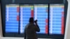 FILE - A man stands in front of a screen showing that multiple departure flights have been cancelled following the outbreak of the coronavirus, at an airport in Wuhan, Hubei province, China, Jan. 23, 2020. 