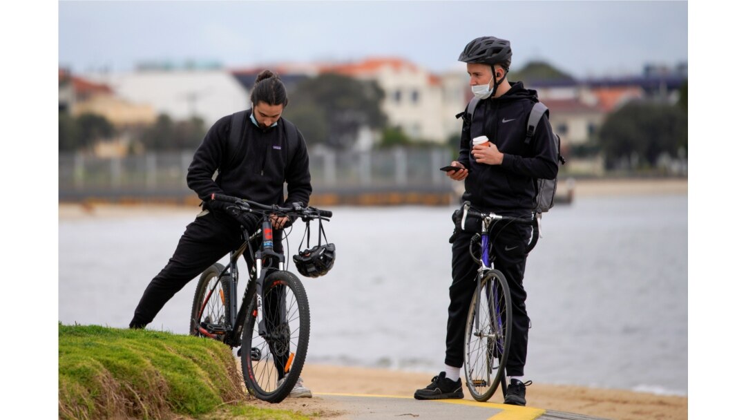 Bicyclists wear face masks at St Kilda beach in Melbourne, the first city in Australia to enforce mask-wearing to curb a resurgence of COVID-19, July 23, 2020.